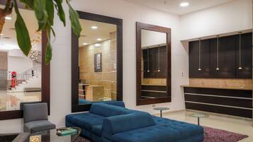 A modern living room with a blue sofa, a glass coffee table, and a large mirror.