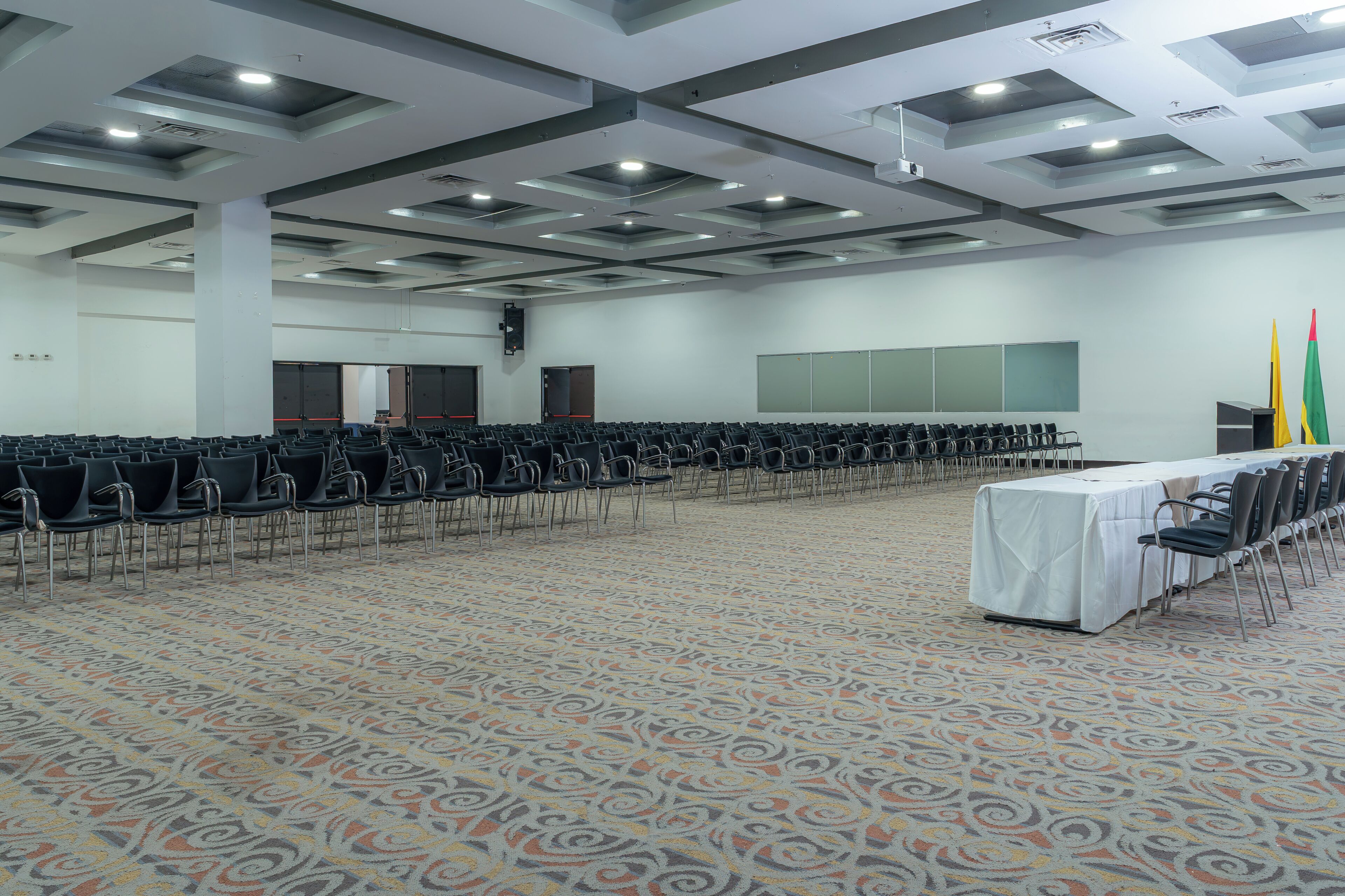 A conference room with rows of chairs, a stage, and a patterned carpet.