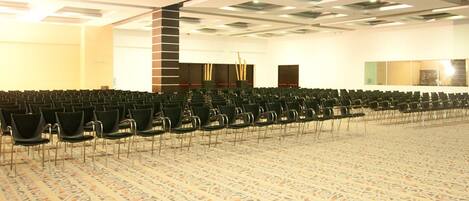 A conference room with rows of chairs, a carpeted floor, and a whiteboard on the wall.