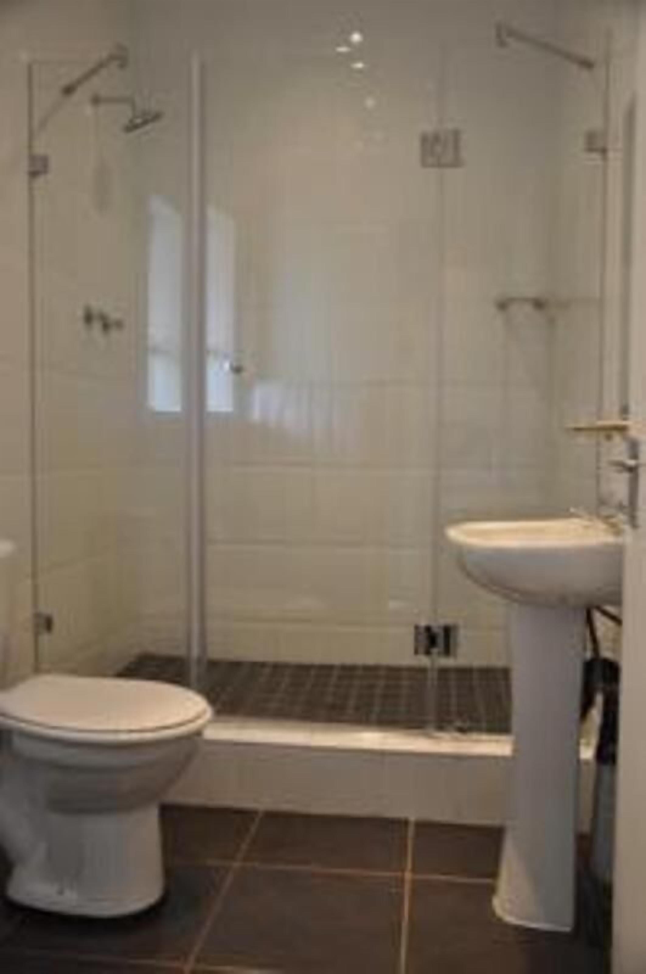 A bathroom with a toilet, a sink, and a glass-enclosed shower area.
