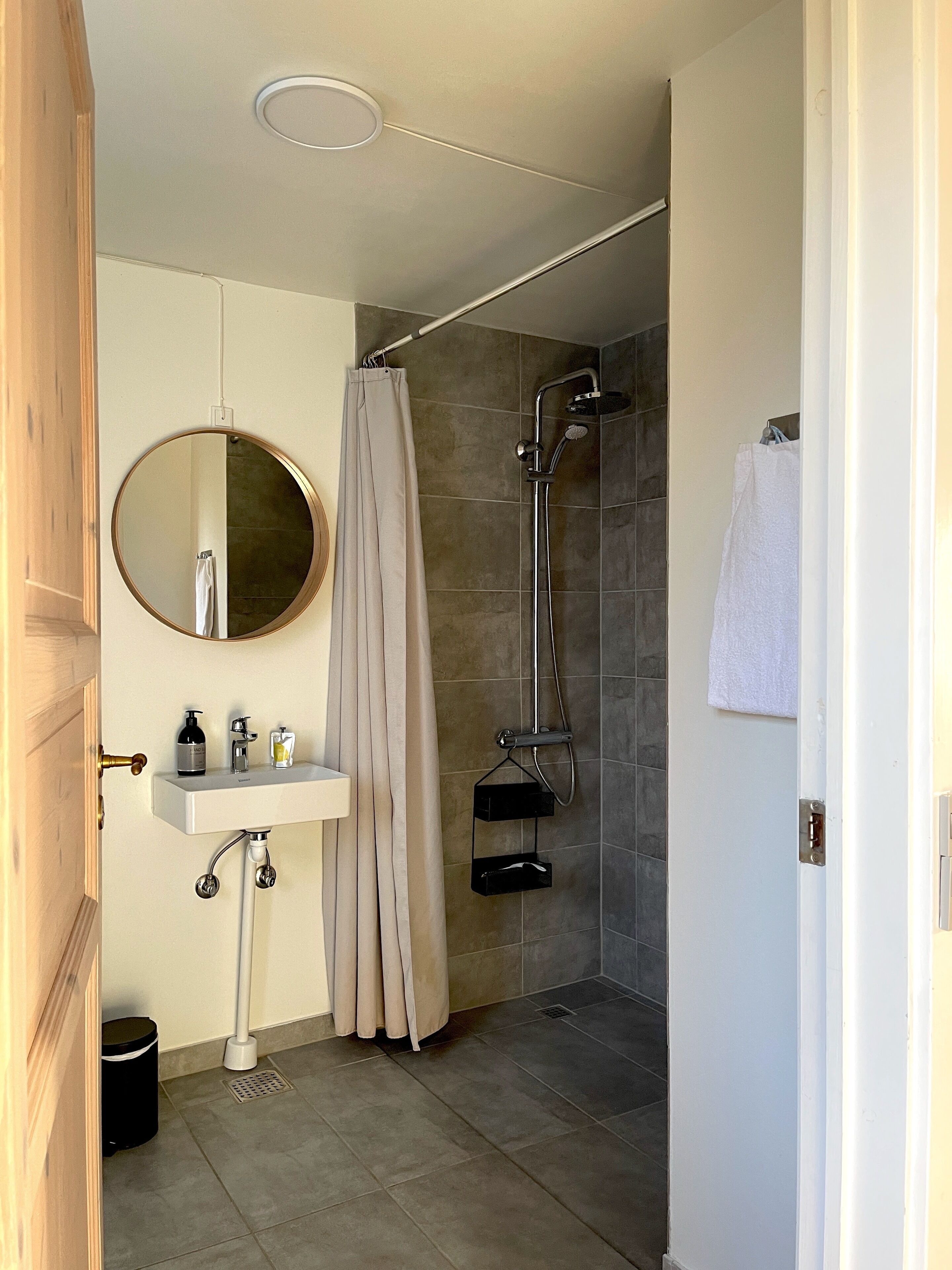 A modern bathroom with a sink, mirror, shower, and toilet.