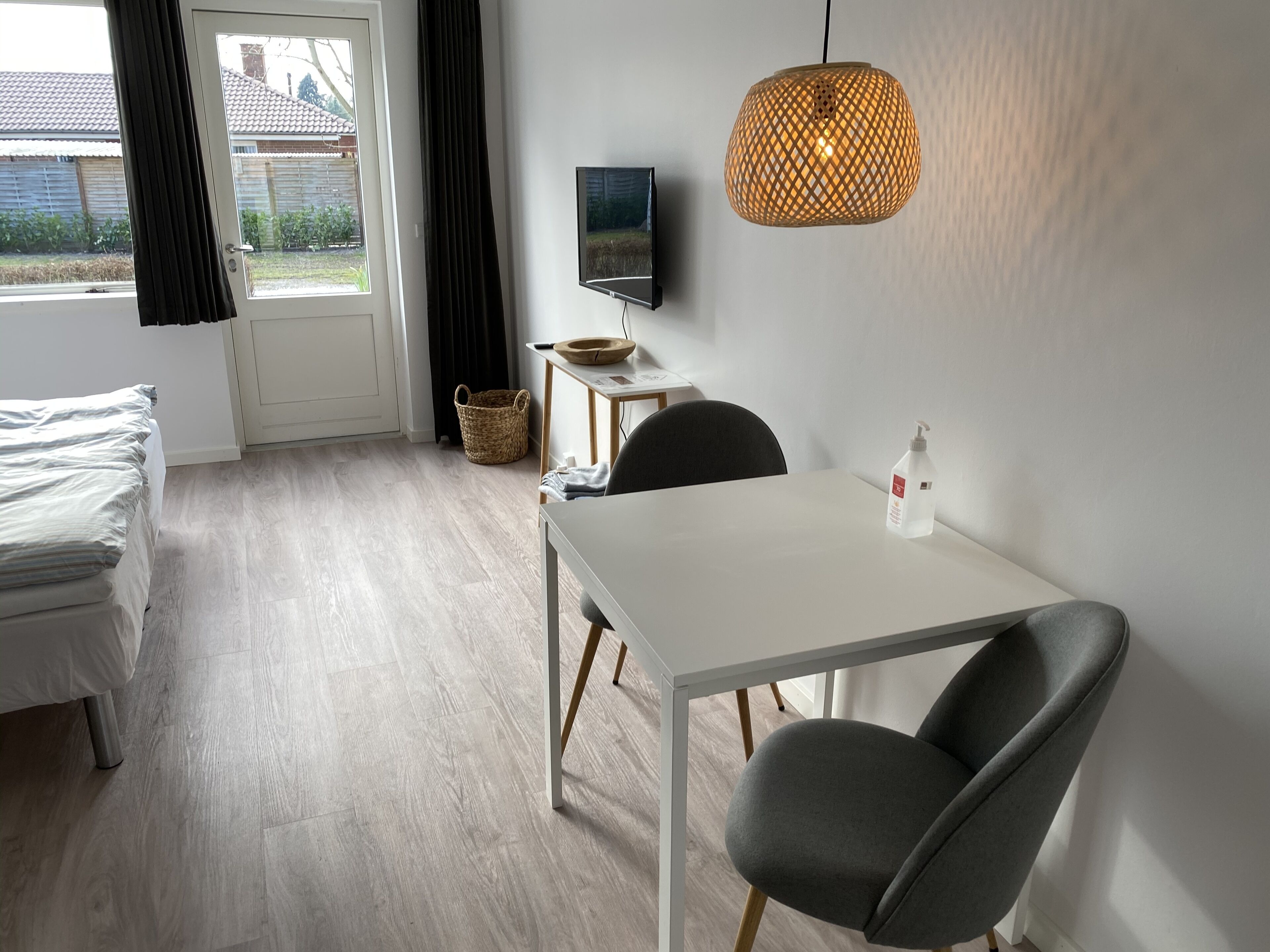 Una habitación moderna con una cama, una mesa con dos sillas, un televisor y una lámpara colgante.