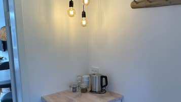 Une cuisine compacte dotée d’un plan de travail en bois, d’une machine à café, de bocaux et d’un lave-vaisselle encastré.