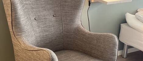 Una sala de estar moderna con un sillón gris, un sofá blanco y suelo de madera.