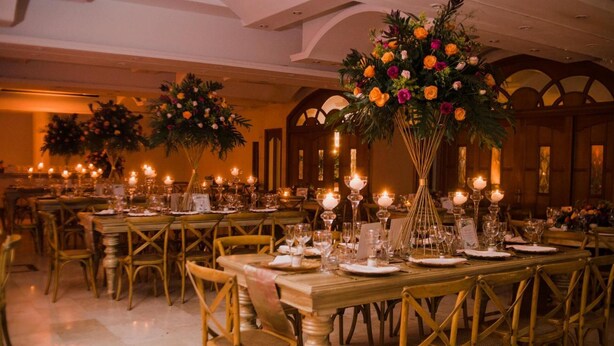 A banquet hall with long tables set for dining, featuring candlelit centerpieces and gold chairs. - Tativan Hotel (Valledupar)
