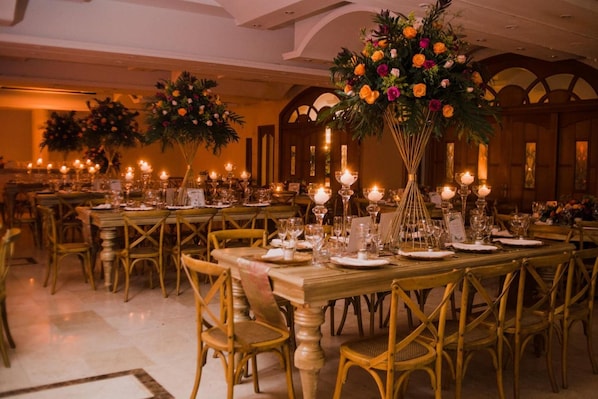 A banquet hall with long tables set for dining, featuring candlelit centerpieces and gold chairs. - Tativan Hotel (Valledupar)