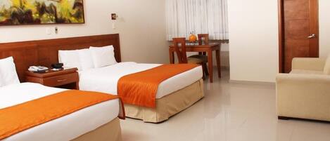 A hotel room with two beds, a dining table, and a sofa.