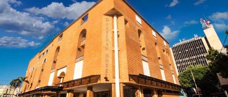 Un gran hotel de varios pisos con una entrada destacada y un cielo despejado.