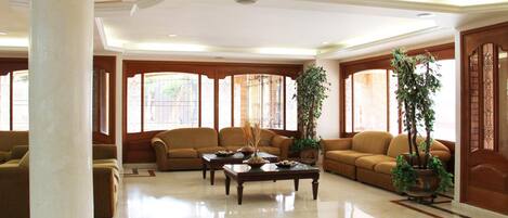 A spacious living room with a large white column, two sofas, a coffee table, and potted plants.