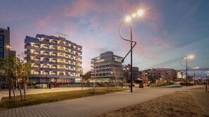 Un hôtel moderne à plusieurs étages, doté d’une terrasse et d’un chemin piétonnier bien éclairé.