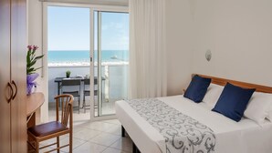 Une chambre d’hôtel avec un lit, une chaise, une table et vue sur la plage.