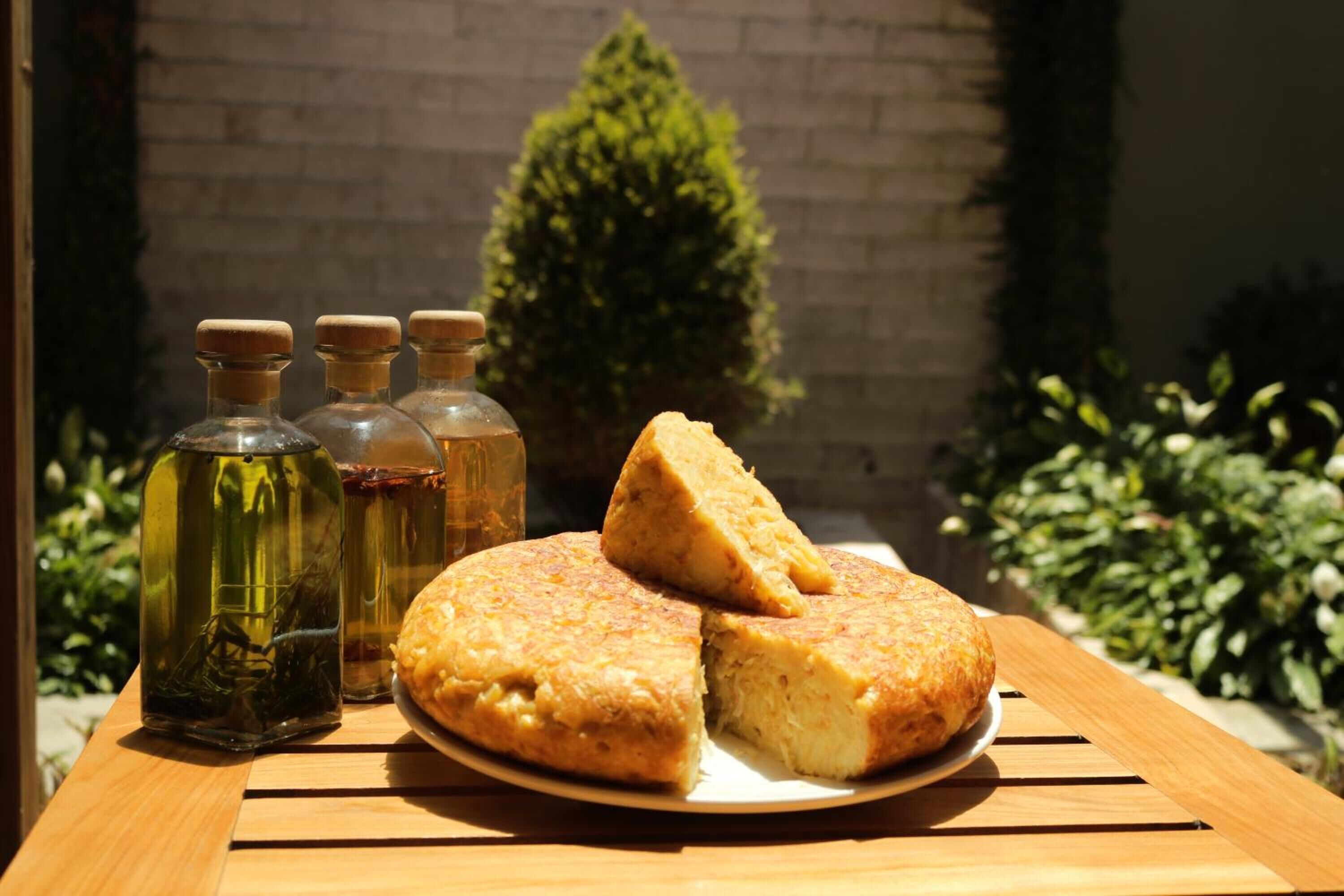 A wooden table with a plate of food and three glass bottles.