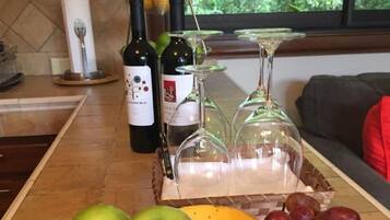 Eine Küchenarbeitsplatte mit einer Obstschale mit Äpfeln und Trauben, einem Bananenkorb und einer Weinflasche.