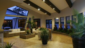 Un espacio habitable amplio con techo alto, ventanas grandes y varias plantas en macetas.