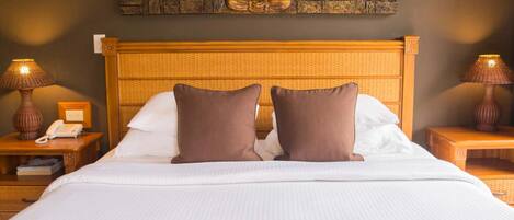 A hotel room with a large bed, two nightstands with lamps, a wall-mounted Buddha sculpture, and a textured headboard.