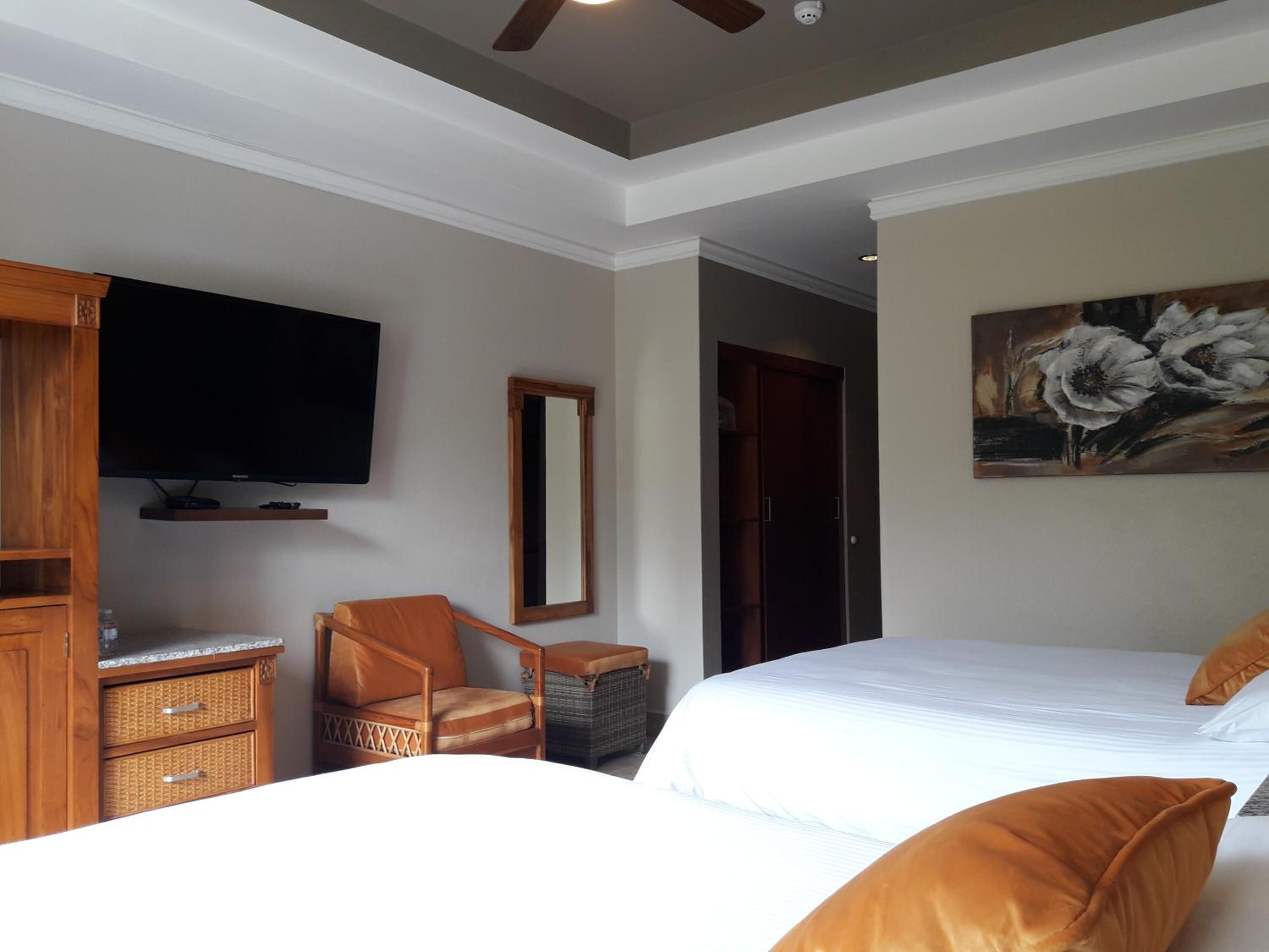 Una habitación de hotel con una cama grande, televisión, una silla y un armario.