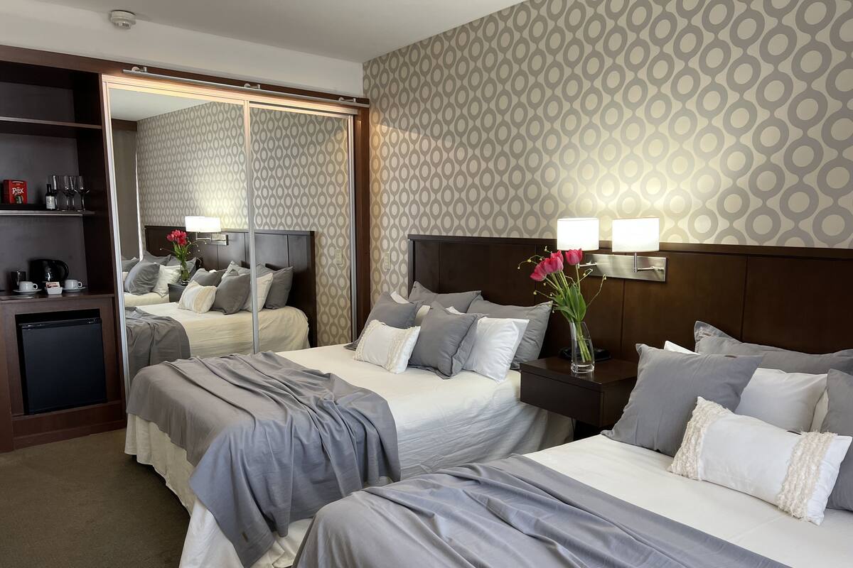 Habitación de hotel con dos camas, un escritorio pequeño, un espejo y un minibar.