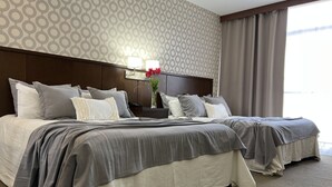 Ein Hotelzimmer mit einem großen Bett, zwei Nachttischen und einem Fenster mit Vorhängen.