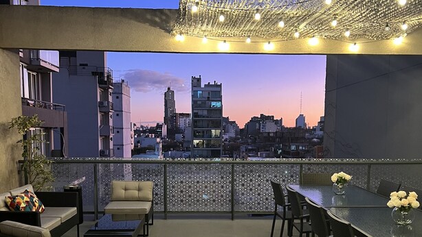 Eine Dachterrasse mit Blick auf die Stadt, ausgestattet mit Sofas, einem Tisch und Stühlen.