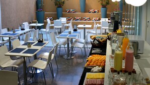 Ein Essbereich mit mehreren Tischen und Stühlen, ein Buffet mit verschiedenen Speisen und Zimmerpflanzen.