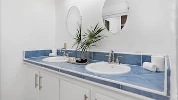 Un baño con dos lavamanos, un espejo grande y una planta en maceta.