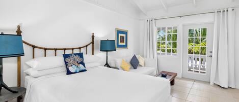 A spacious bedroom with a large bed, a ceiling fan, and a view of the outdoors through a sliding glass door.