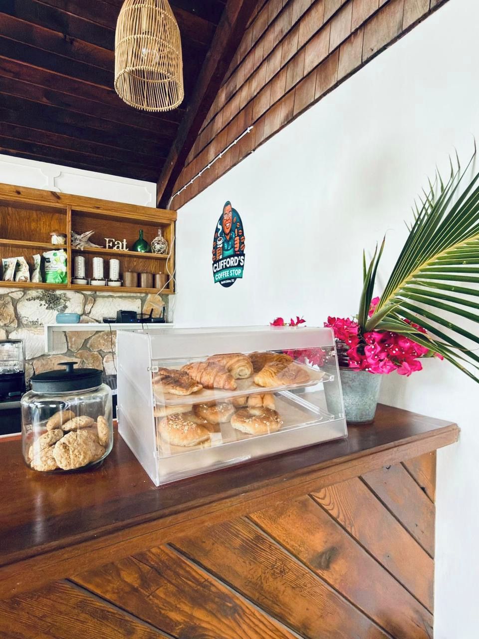 Een bakkerijdisplay met gebak en koekjes, een bord van een koffiebar en een houten toonbank.