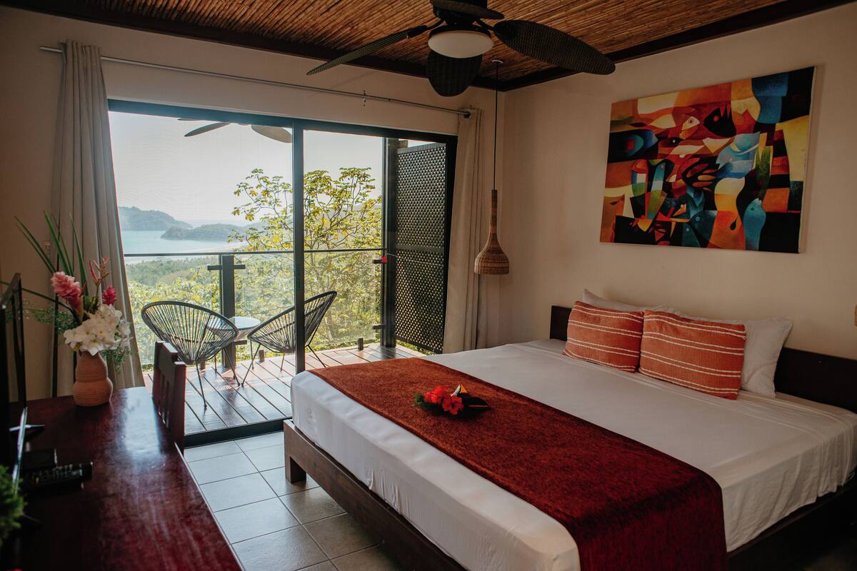 Un dormitorio con una cama grande, vistas al exterior y un cuadro en la pared.
