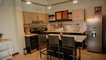 A modern kitchen with a central island, dark cabinetry, and pendant lighting.