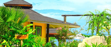 A building with a sloped roof, surrounded by lush greenery and a clear sky.