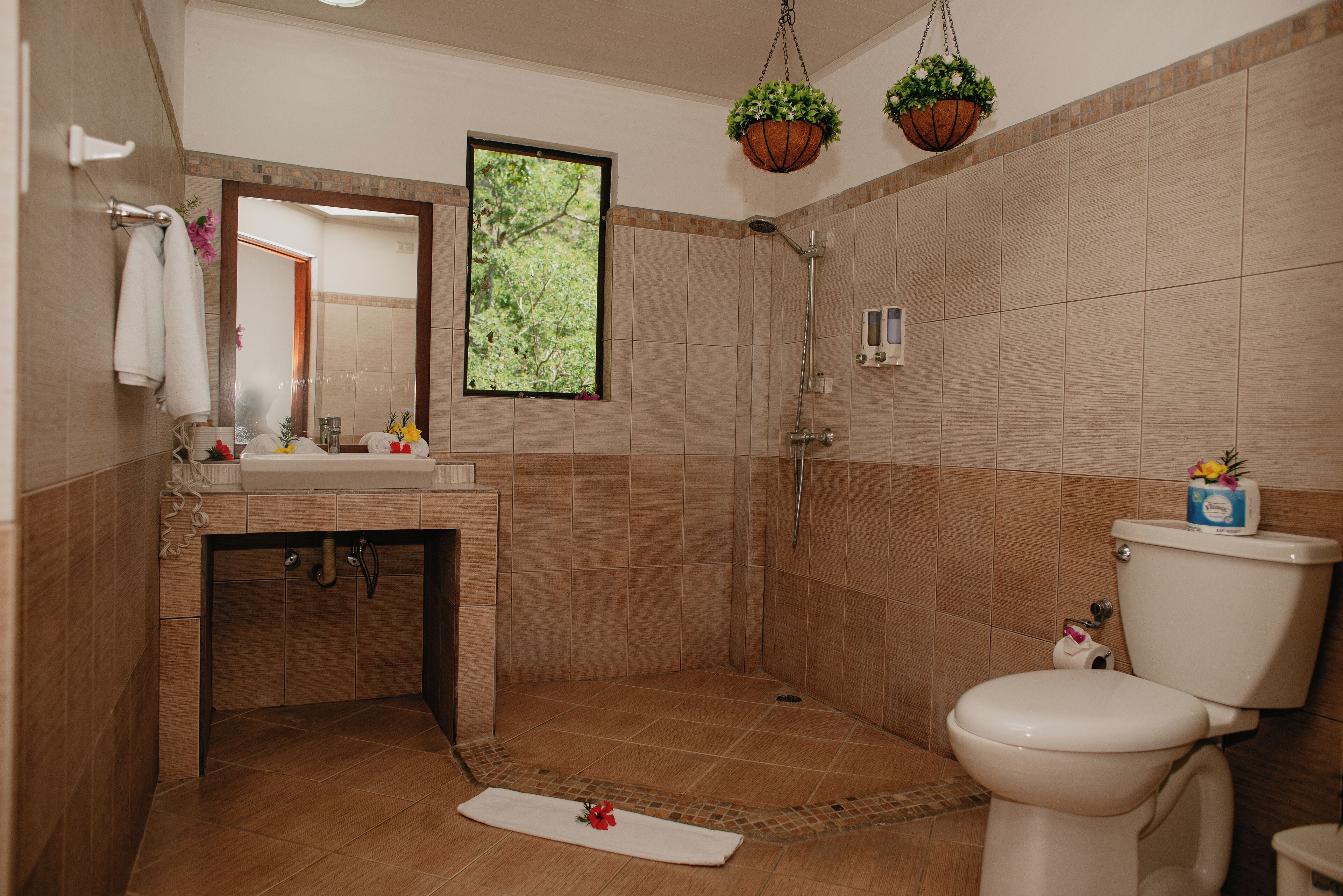 Un bagno con doccia, WC, lavandino e specchio.