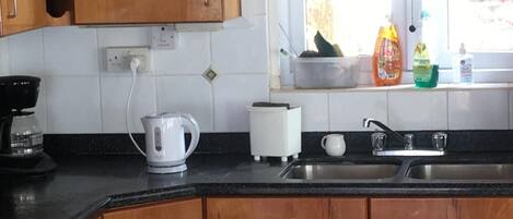 Une cuisine avec des meubles en bois, une machine à café, un grille-pain et une fenêtre donnant sur l’extérieur.