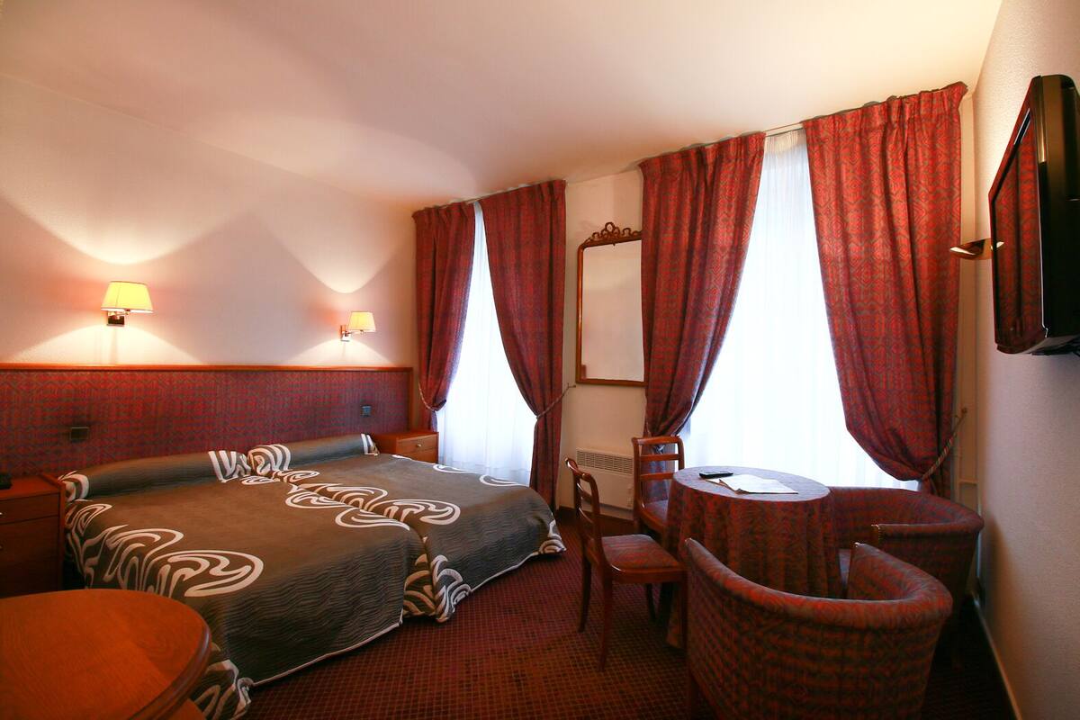 Habitación de hotel con dos camas, un escritorio, una silla y un espejo.