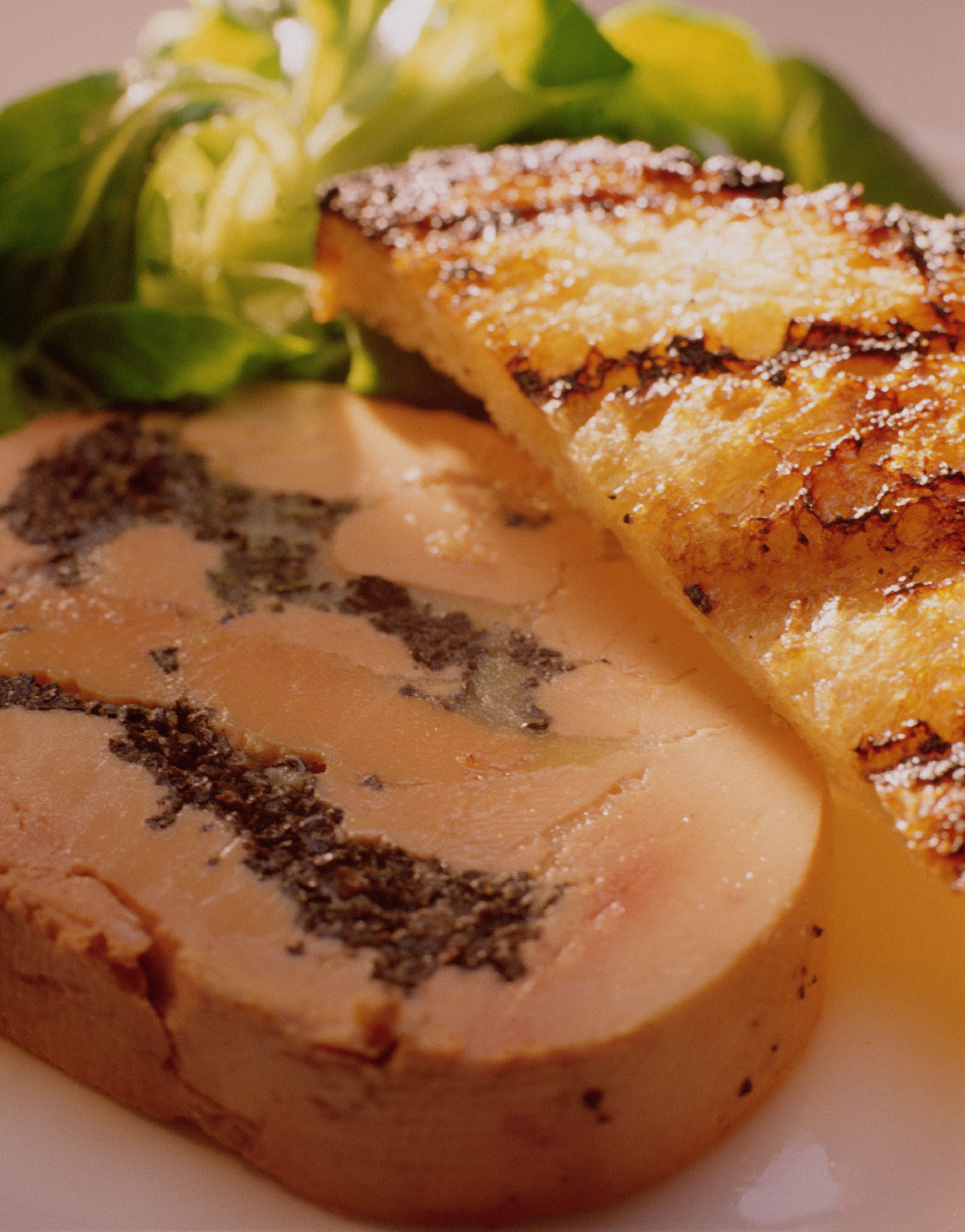 A close-up of a dish with grilled bread and a slice of meat topped with poppy seeds.