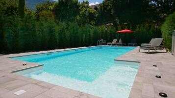 Relax by the pool surrounded by lush greenery and a scenic mountain view.