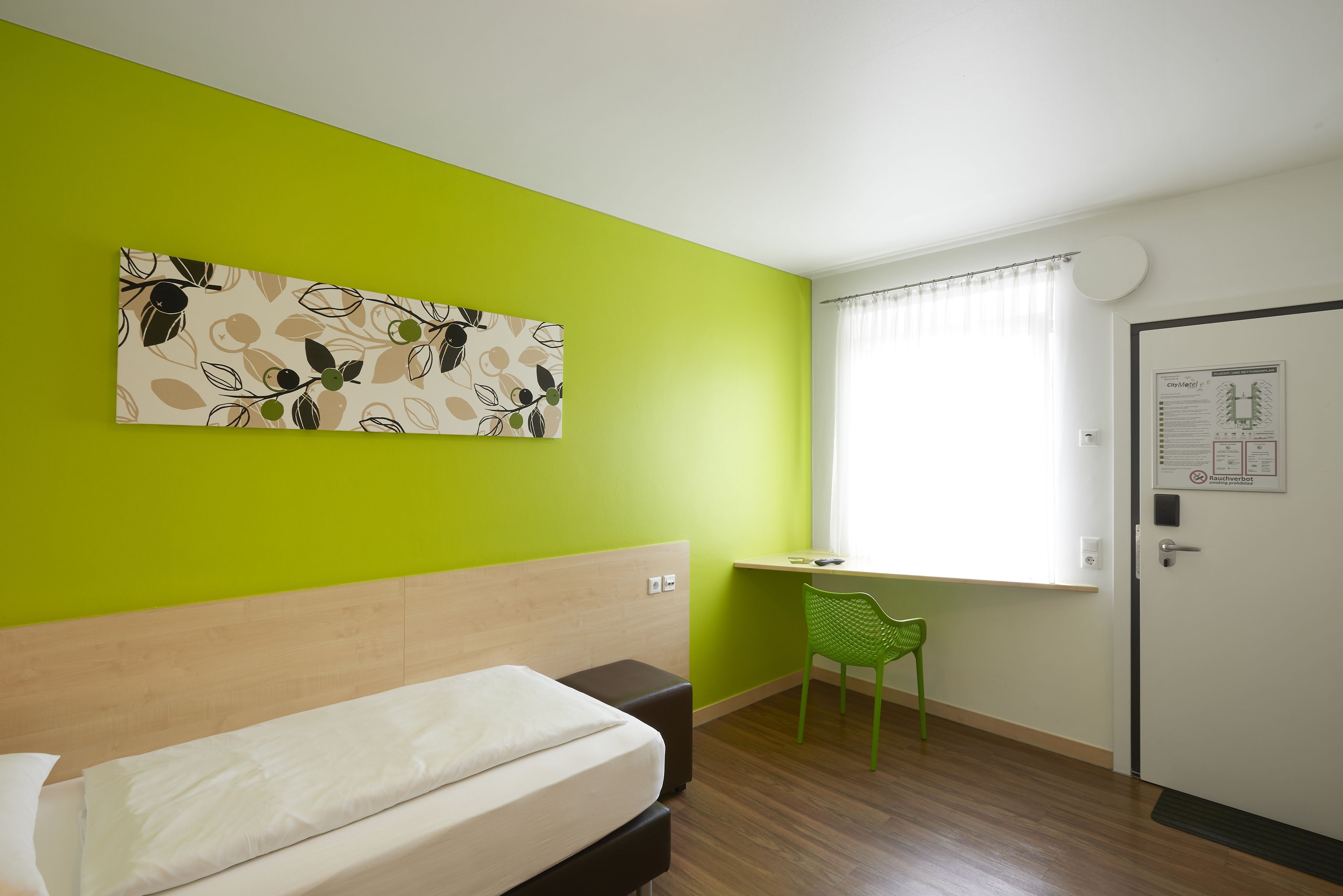 A room with a bed, a desk, a chair, and a door.