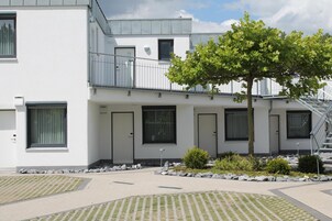 Un edificio moderno con techo plano, varias puertas y un árbol en el patio.
