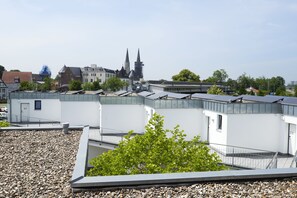 A modern building with multiple white facades, a visible church spire, and a tree in the foreground. - CityMotel Soest (Soest)