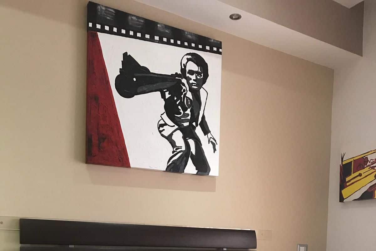 A hotel room with a bed, a large painting on the wall, and a towel sculpture on the bed.