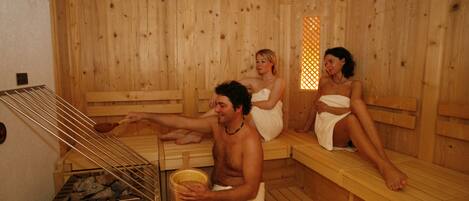 A sauna with wooden benches and a central heating element.