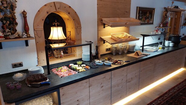 Un'impostazione buffet con diversi piatti, un arco decorativo e un muro in legno con uno scaffale sospeso.