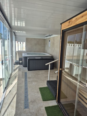 Un moderno espacio de spa con un jacuzzi, una mesa de masaje y una sala acristalada.