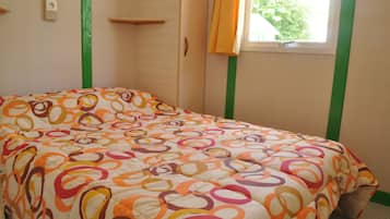 Ein Schlafzimmer mit Bett, einem Fenster mit Vorhängen und einem an der Wand befestigten Regal.