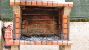 Un horno para pizza de ladrillo con chimenea, un extintor y una rejilla de metal.