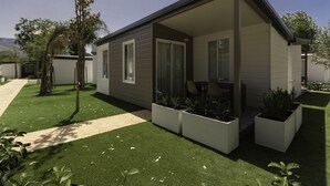 A modern single-story house with a covered porch, a paved driveway, and a well-maintained lawn. - Camping Los Llanos (Denia)