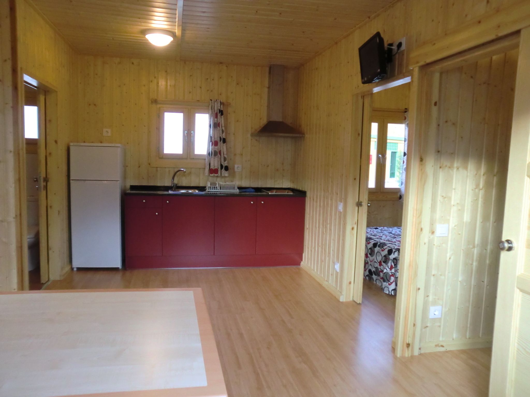 Eine Holzdiele mit Küchenbereich, inklusive Kühlschrank, Spüle und Schränken.