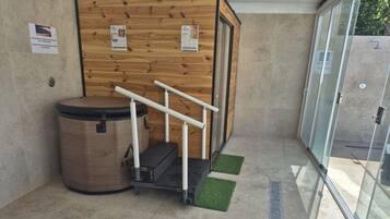 A modern bathroom with a wooden wall, a trash bin, a shower area, and a glass door leading outside.
