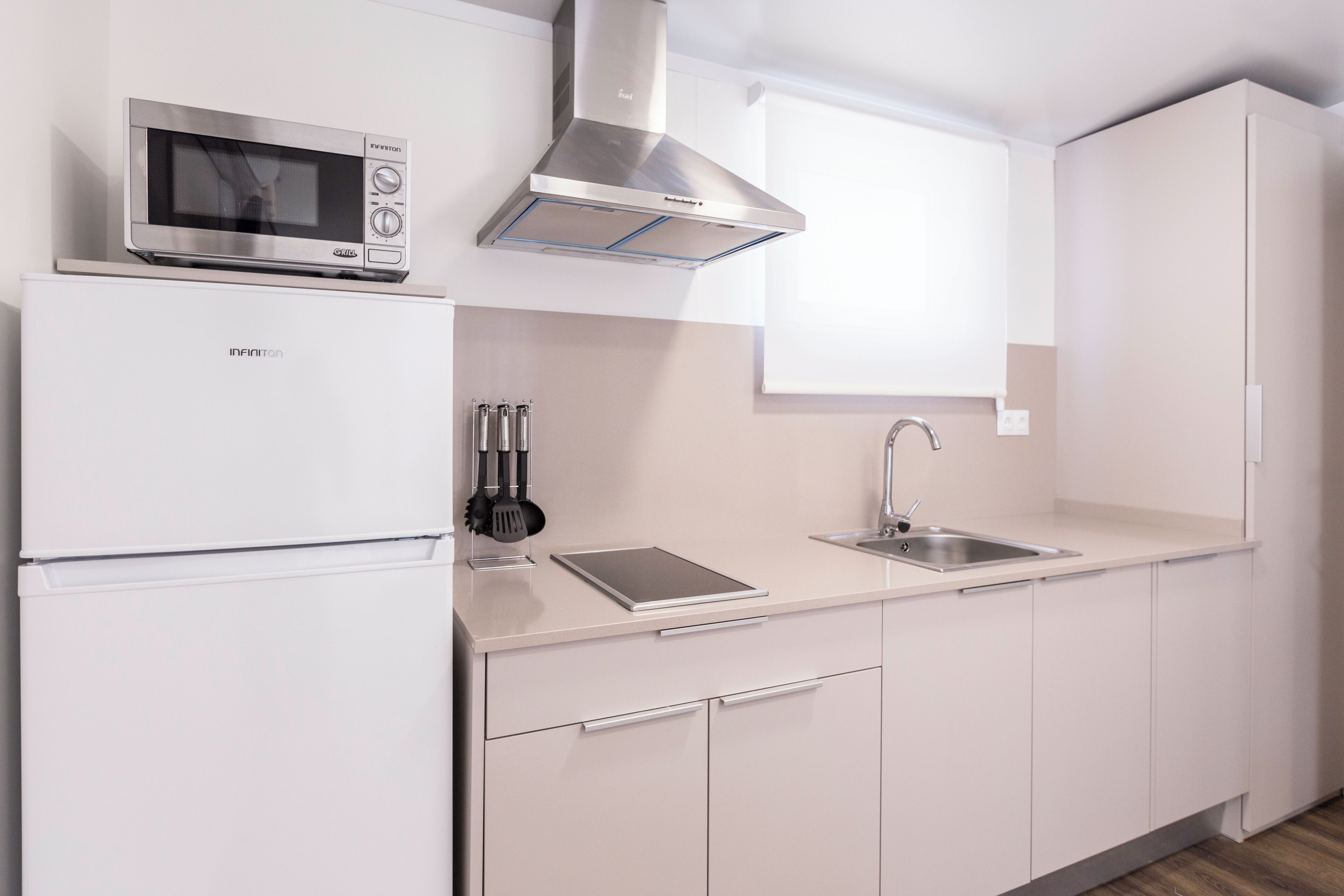 A modern kitchen with a built-in microwave, stainless steel range hood, and a sink.