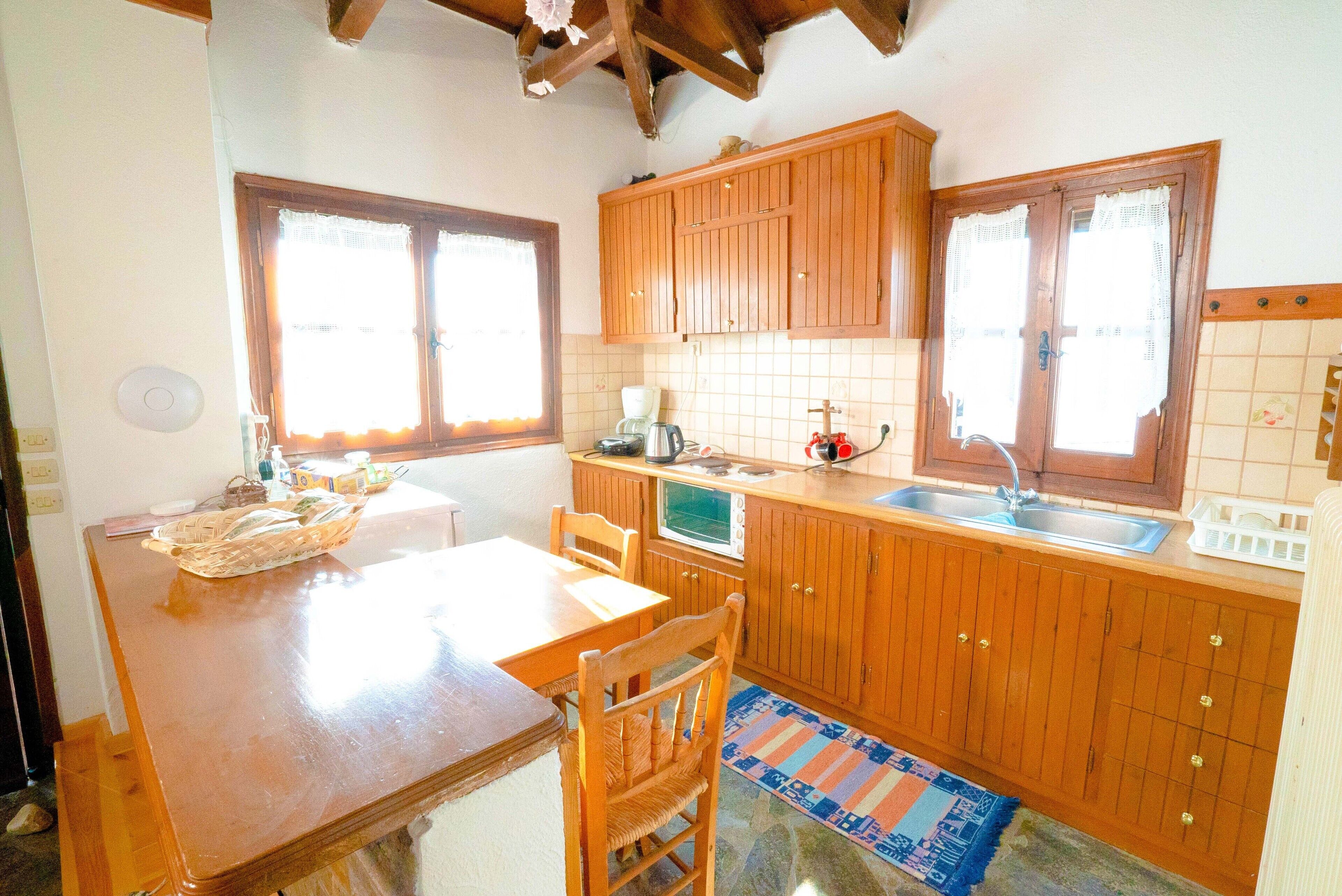 Una cocina con armarios de madera, microondas, fregadero y una mesa de comedor con sillas.
