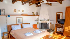 Ein Schlafzimmer mit einem großen Bett, einem Fernseher, einem Kamin und einer Holzbalkendecke.